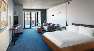 Photo of one king bed, living space and balcony.