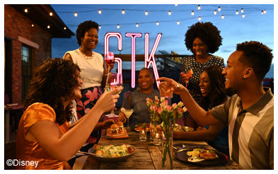 Image of seven friends dining and laughing together at STK Steakhouse. 