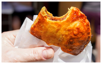 Cooked beef in a pastry wrapped in paper.