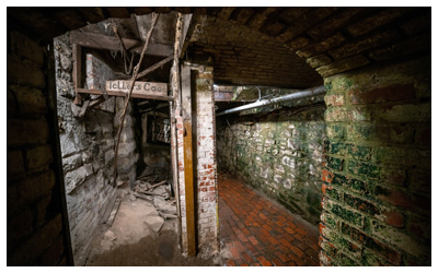 Underground enclosed walkways with bricks and piping.