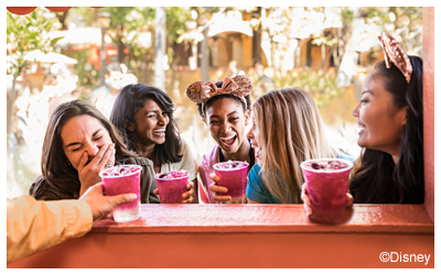 A group of women buying colorful drinks.